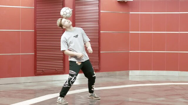 Football freestyle. Teenager guy football soccer player practicing tricks, kicks and moves with ball. Professional football freestyler athlete stuffing kicking the ball and making cool tricks. Sport