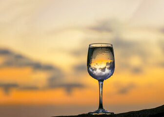 Glass of Wine on rock with beautiful clouds of sunset in background .
