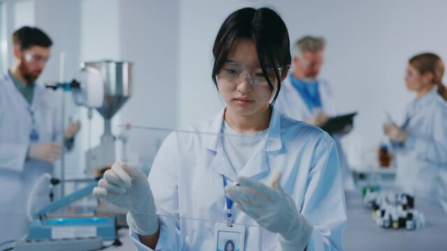 Female asian scientist using professional pc tablet innovative computer mock-up touchscreen hologram app while working at medical laboratory science center.