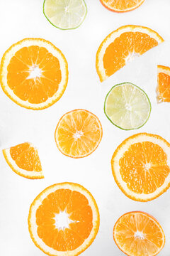 Slices of orange, tangerine and lime are flying against the white background. Citrus fruit backdrop