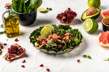 Obraz na płótnie Canvas Winter Salad with quinoa, spinach, avocado, grapefruit, pomegranate, nuts and microgreens, prepare in process vegan salad in home kitchen