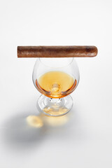 Closed up view of glass of whiskey with cigar on top on white back