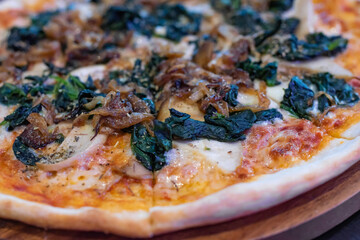 side view, italian pizza with fried onions, green spinach and mushrooms on koh samui in thailand