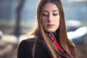 Outdoor portrait photo of cute blonde girl in black jacket and red scarf