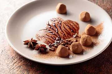 Chocolate truffles on a beige plate with chocolate sauce.