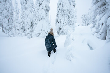 Young woman walking in deep snow in a forest