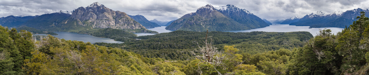 An ultra wide panorama of a cloudy day in the wilderness of Patagonia surrounded by mountains, water and trees seen from Cerro Llao Llao viewpoint - obrazy, fototapety, plakaty