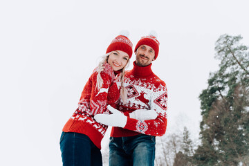 Beautiful couple in knitted sweaters on the background of the winter forest.