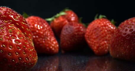 Fresh summer Strawberries on wet black surface with droplets. Large berries. Strawberries close-up. 