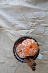 Enamel mug filled with fresh peeled tangerines and cinnamon sticks. Top view.