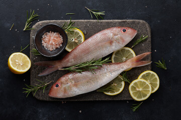 Fresh red mullet fish cooking on black background, top view