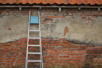 A large ladder against the wall of an old brick building 