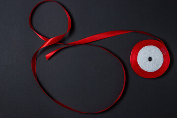 Red ribbon on a black background. Background for the inscription and logo. Textile material