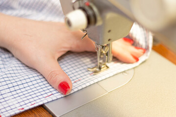 Woman taylor is working on a sewing machine