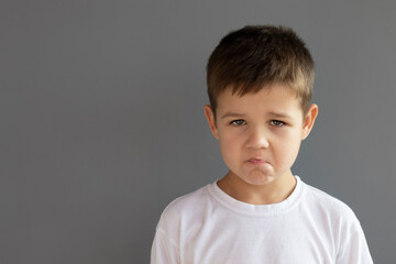 Offended little boy , on gray background