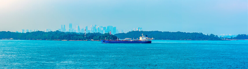 Commercial shipping passing the lighthouse in the Singapore Straits in Asia in summertime