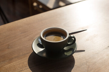 cup of espresso with shadow on wooden table.