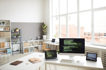 Image of workplace with computers and digital tablet with software on the screens in modern office