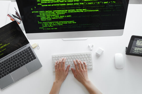 High angle view of developer typing on computer keyboard installing the new system on computer at the table