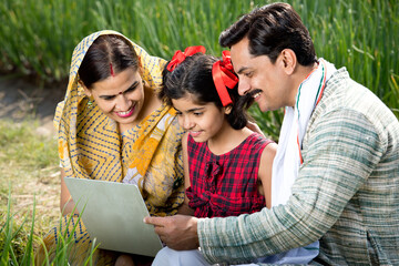 Rural family using laptop on agriculture field