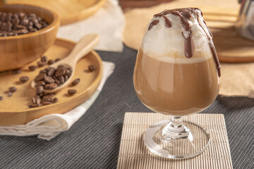 iced mocha coffee served with whipped cream topping and chocolate syrup in wine glass place on wooden table