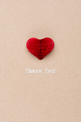 International Thank you day. Greeting card with craft red paper heart on natural beige background. Flat lay, top view.