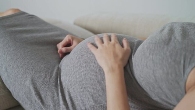 asian pregnant woman touching belly with care and baby in abdomen moving.