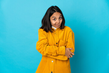 Young latin woman isolated on blue background making doubts gesture while lifting the shoulders