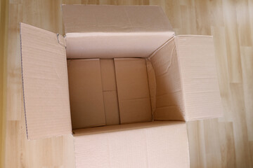 there is an empty open cardboard box on the floor, concept of mailing, package, online shopping, waste paper, renewable product, recycling