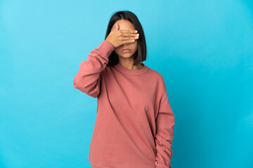 Young latin woman isolated on blue background covering eyes by hands. Do not want to see something