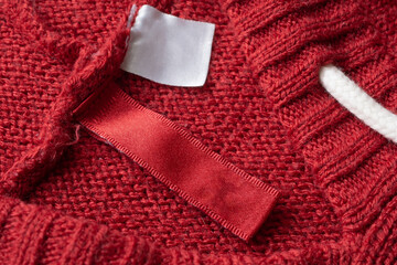 Blank laundry care clothes label on red knitted fabric texture background