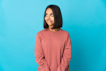 Fototapeta premium Young latin woman isolated on blue background having doubts while looking up