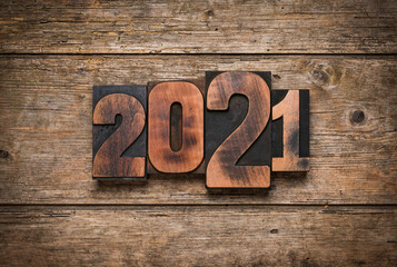 Year 2021 written with letterpress printing blocks on rustic wooden background