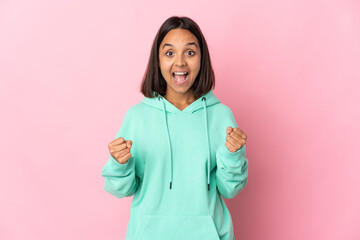 Young latin woman isolated on pink background celebrating a victory in winner position