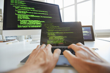 Close-up of computer programmer typing codes for new software on laptop