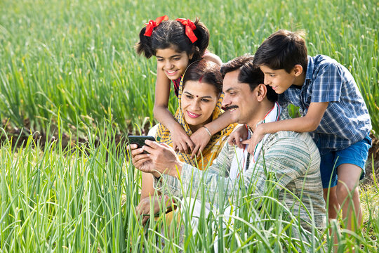 Rural family using mobile phone on agriculture field