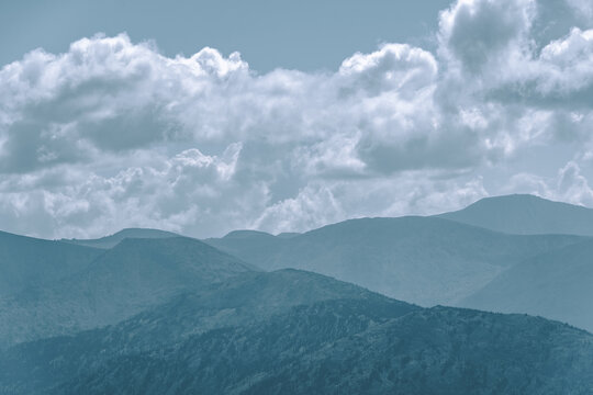 Thick clouds over mountain range, hills in blue haze