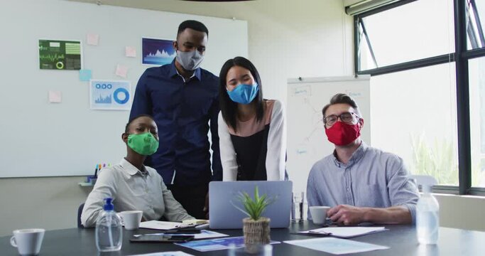 Portrait of office colleagues wearing face masks in meeting room at modern office