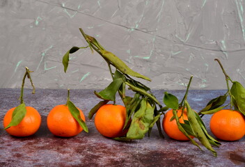 Fresh mandarin, clementine, tangerine with green leaves on a rusty surface background