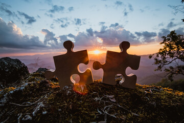 Close-up of wooden jigsaw puzzle on a rocky mountain connecting jigsaw puzzles with sunlight...