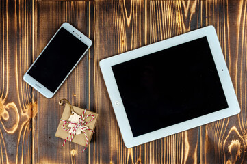 Smartphone, tablet, gift, wooden Christmas tree on a wooden background .