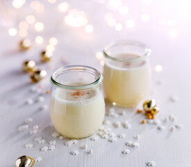 Festive eggnog sprinkled with nutmeg in glass dishes on a light background