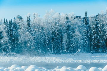 Boulders in cold water are covered with snow. Winter river on frosty morning.