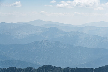 View of calming mountain valley with ridge on horizon. Gentle hills in blue haze.