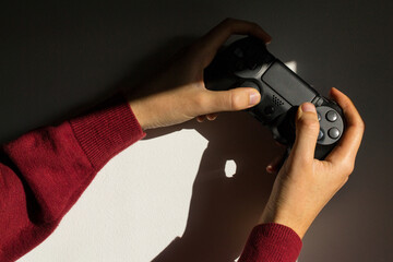 Hands holding a video game joystick. Hard light with pronounced shadows. Gamer concept. © Francisco Toledo
