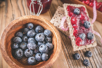 Bowl of blueberries with toast and spread jam on wooden table
