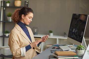 Serious female designer working with photos at her workplace with computer monitor on it at office