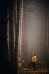Fototapeta na wymiar Young man taking a brake during biking through autumn forest