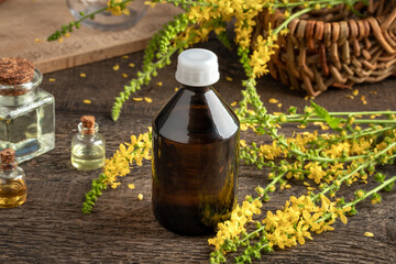 A bottle of tincture with fresh blooming agrimony, with essential oils