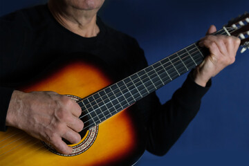 Obraz premium man plays the guitar, close-up hands, the concept of creativity, learning to play musical instruments, online learning